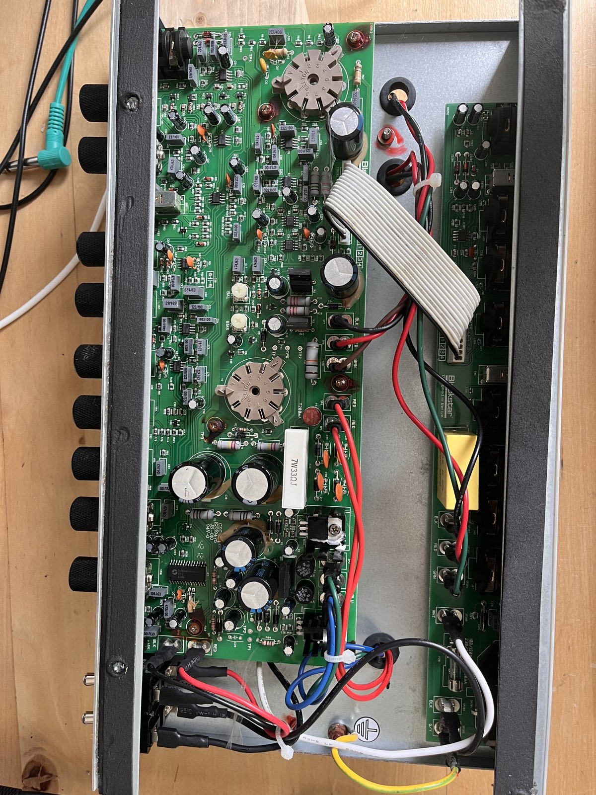 The chassis of the Blackstar HT-5R out of its cabinet, showing the main circuit board with two valve bases, large capacitors and a ribbon cable to the second board.