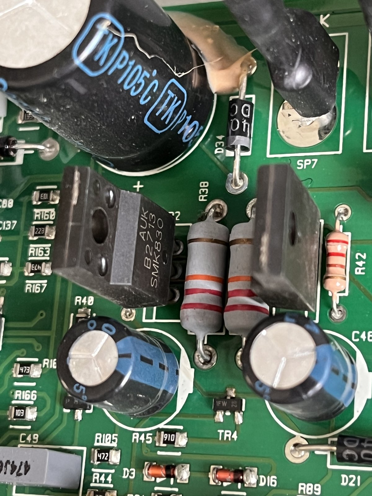 Close-up of the circuit board showing the two original transistors, marked AUK SMK830, either side of a pair of grey resistors, with large capacitors alongside.