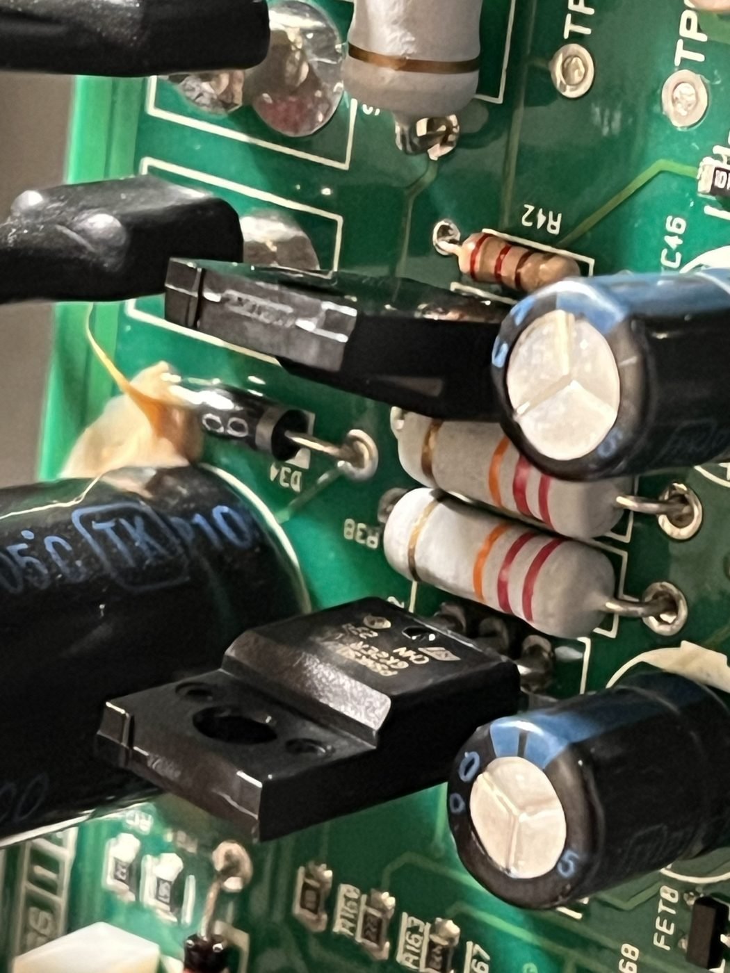 The new transistors fitted on the board, next to two grey resistors and large capacitors.