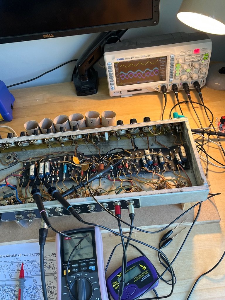 Oscilloscope, multimeter and ESR meter connected to an open amp chassis during diagnosis