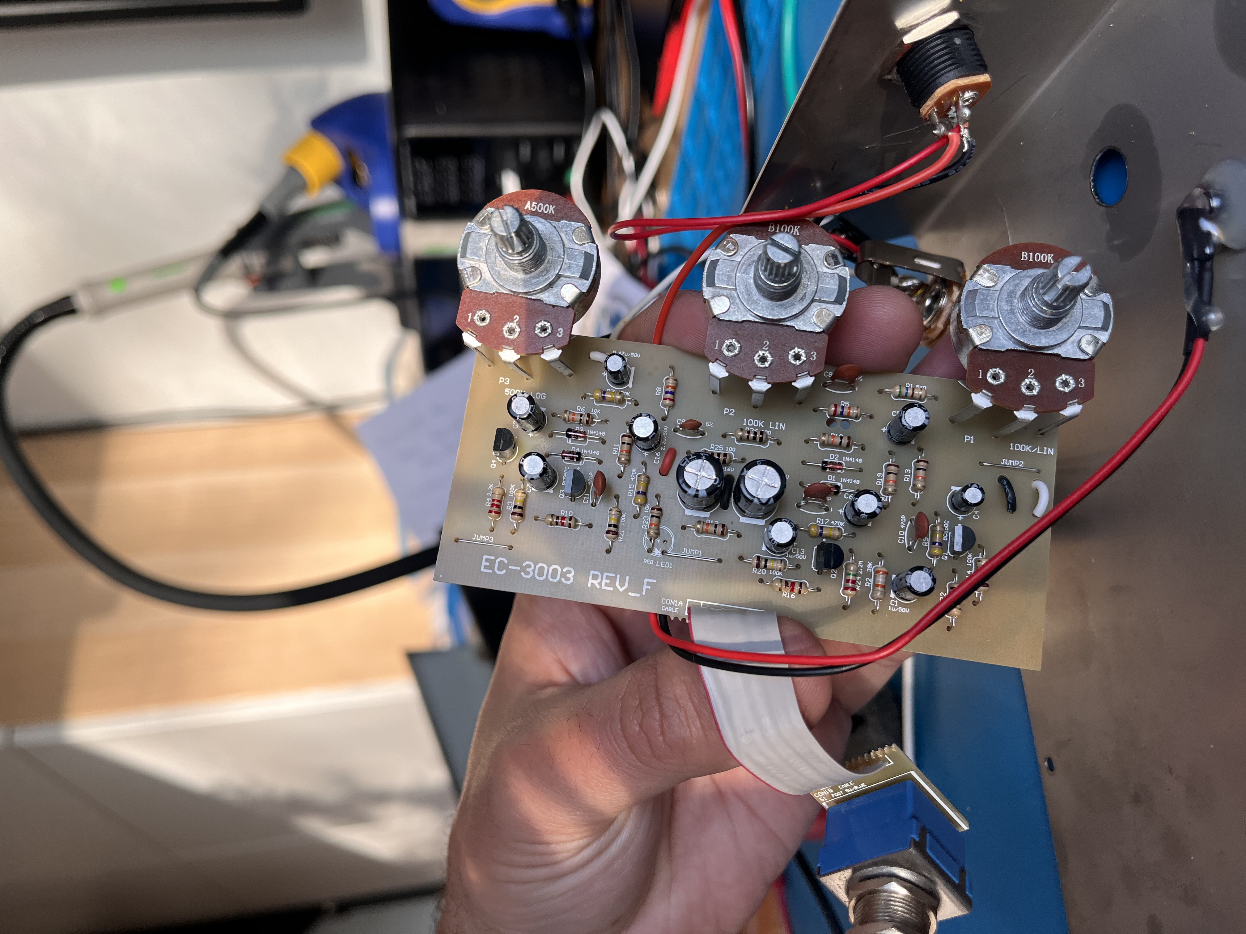 Pedal PCB held up showing components and pots during repair